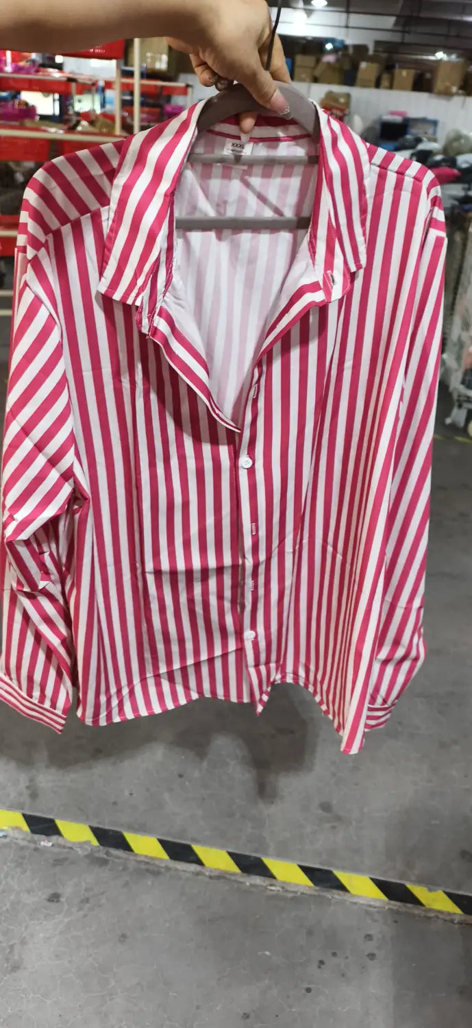 Chemise décontractée à manches longues rayée verticalement rose et blanc pour hommes, à patte boutonnée et col, suspendue sur un cintre.