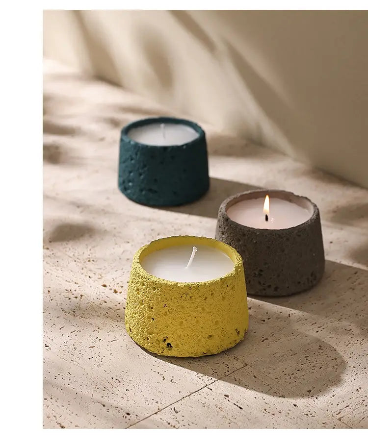 Trois supports de bougie en ciment texturé, en sarcelle, gris et jaune, en béton moucheté, conçus pour un usage en aromathérapie.