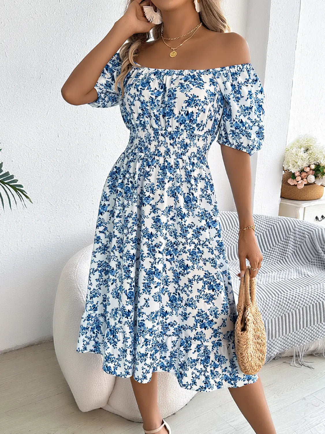 Robe d’été blanche décolletée, avec motifs floraux bleus, manches courtes bouffantes et encolure carrée.