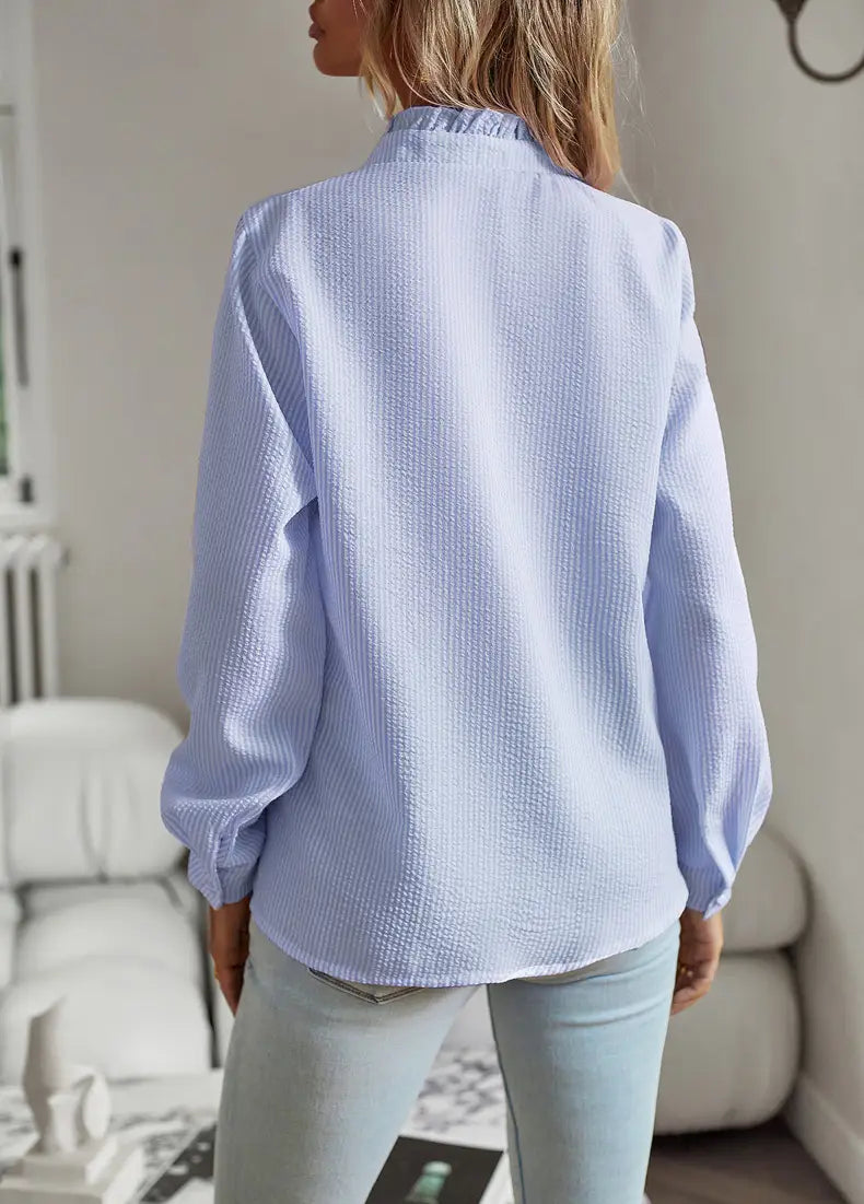 Light blue textured long sleeve button up blouse with a subtle striped pattern and ruffle trim detailing.