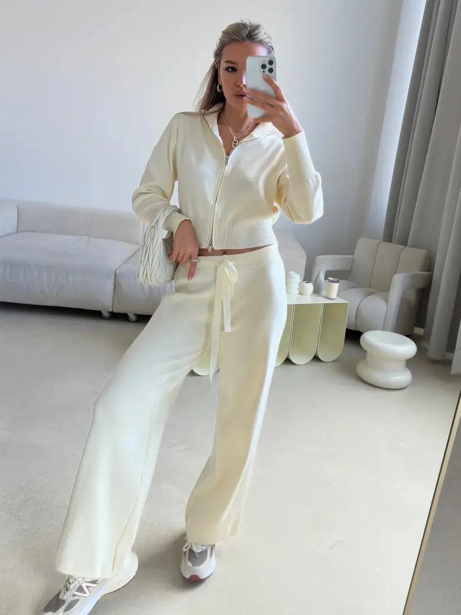 Cream-colored knit zip-up hoodie with fringe detailing on the sleeves from the women’s knit zip up cardigan and wide leg pant set.