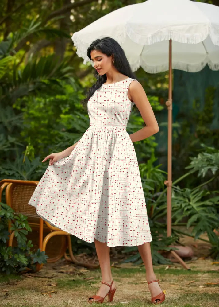A woman wears a be mine white heart print 1950s cotton midi dress with a fitted bodice and flared skirt