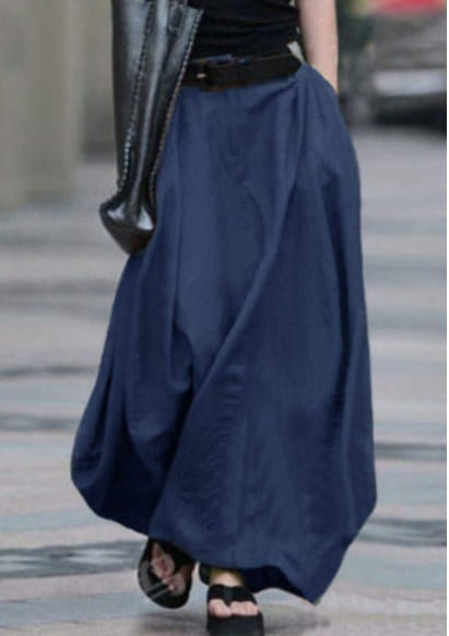 Une jupe longue maxi en satin taille haute bleu marine fluide, avec une silhouette drapée et décontractée et une ceinture noire à la taille.