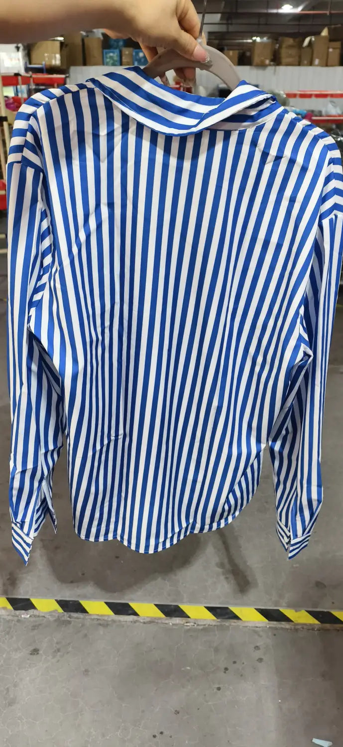 Chemise décontractée à manches longues rayée verticalement bleu et blanc pour hommes, réalisée dans un tissu léger et suspendue sur un cintre.