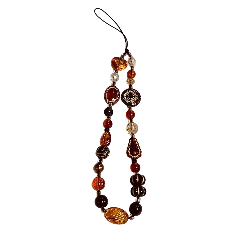 A beaded phone charm strap with amber orange and dark brown glass beads and intricate floral crystal designs