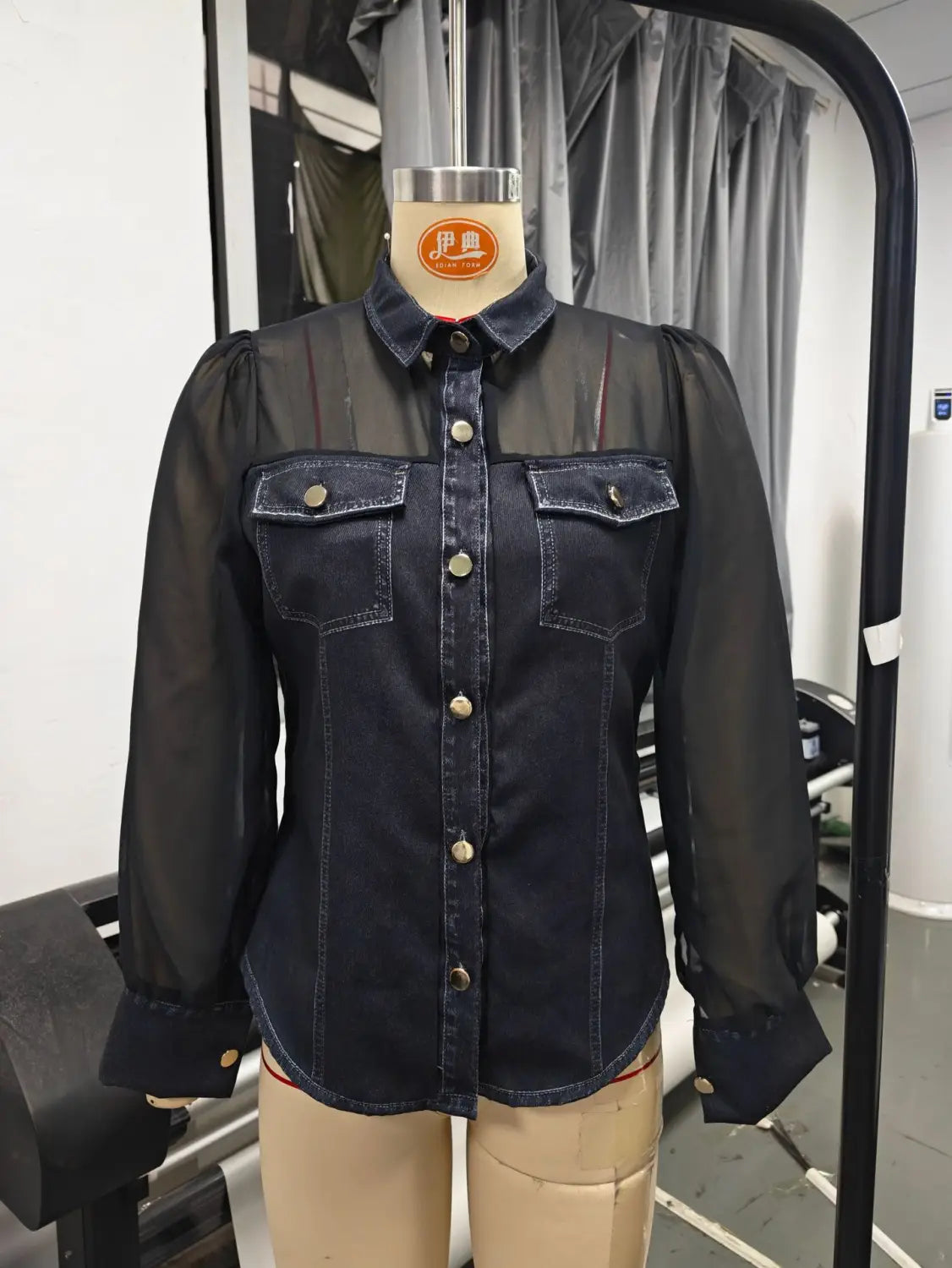 Chemise en denim bleu foncé avec manches longues transparentes noires et poches avant boutonnées, présentant une conception à encolure en V.