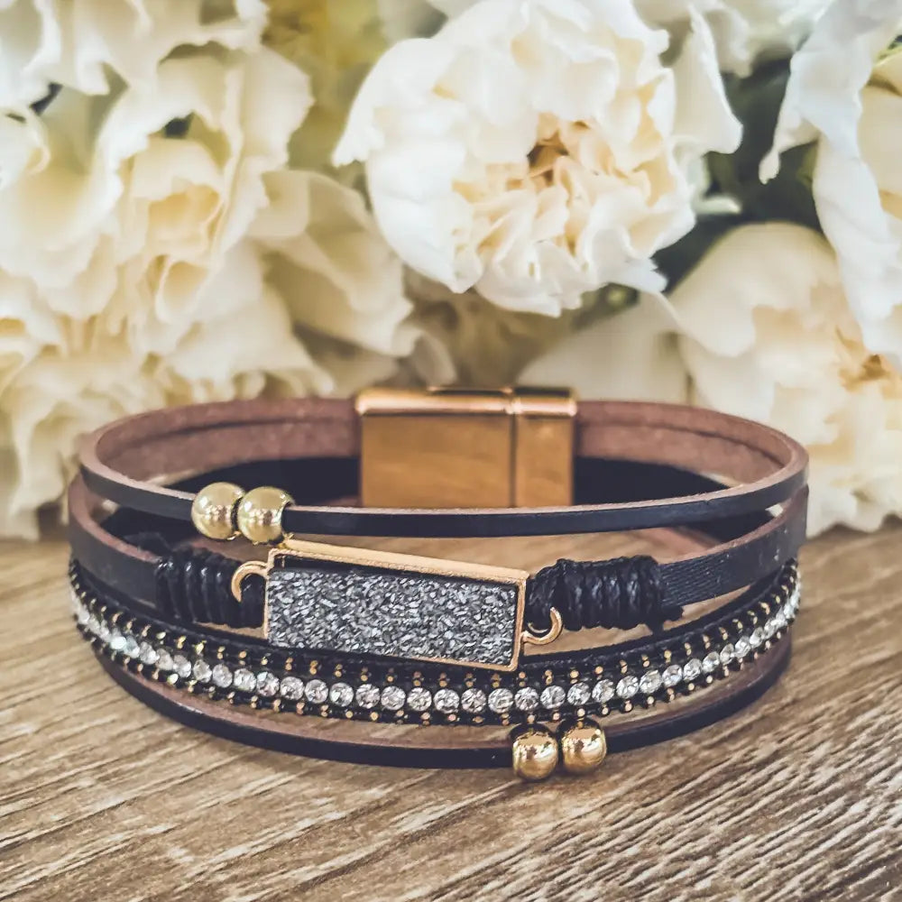 Crystal layered black leather bracelet with gold-toned magnetic clasp, glittery charm, and beaded accents