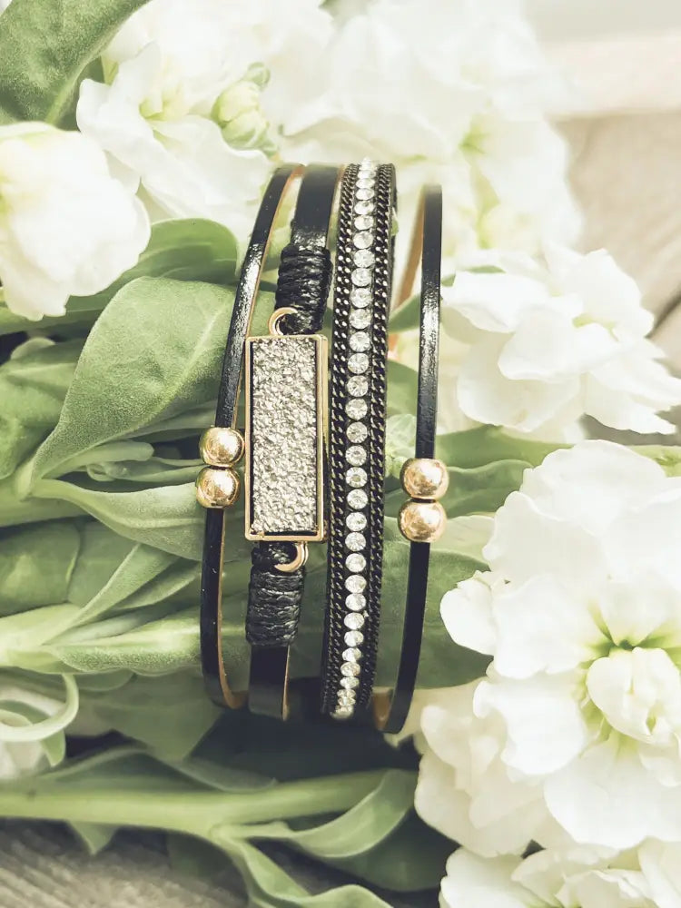 Crystal layered black leather bracelet with gold-tone hardware, textured rectangular charm, and beaded detailing