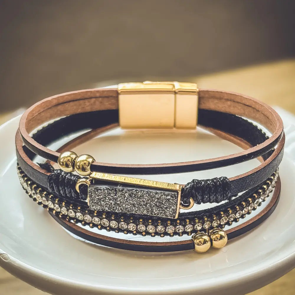 Crystal layered black leather bracelet with gold-toned magnetic clasp, black beads, rhinestones, and metallic accents