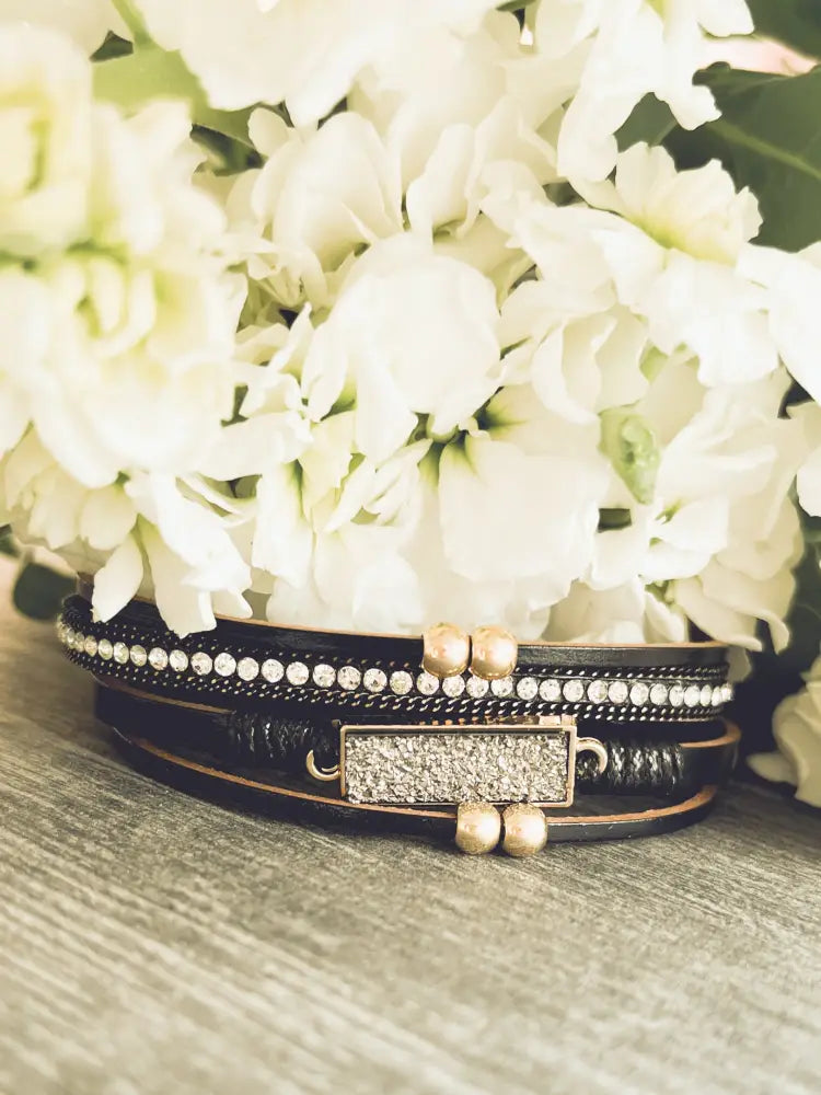 Crystal layered black leather bracelet with gold accents featuring sparkling rhinestones and gold toned beads