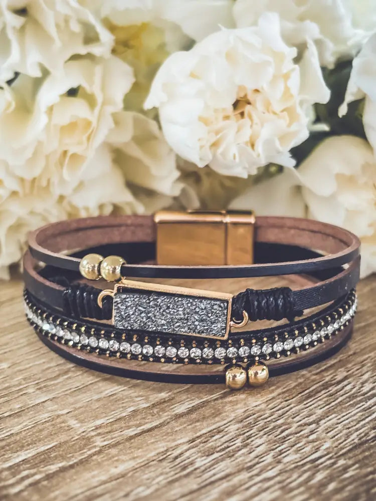 Crystal layered black leather bracelet with gold accents featuring multi-strand design and glittery rectangular charm