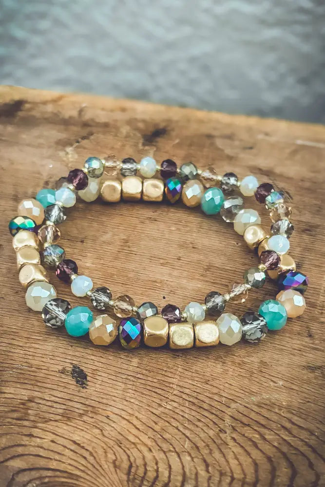Bohemian earth tone iridescent beaded stacking bracelet set with gold-toned, turquoise, and iridescent beads in intricate pattern