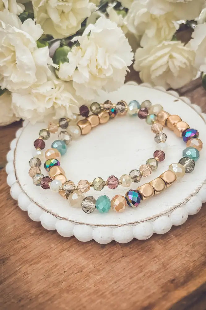 A delicate bohemian earth tone iridescent beaded stacking bracelet with gold-toned and glass beads in teal amber and burgundy