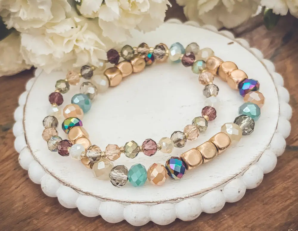 A pair of bohemian earth tone iridescent beaded stretch bracelets with gold metallic beads and glass crystals