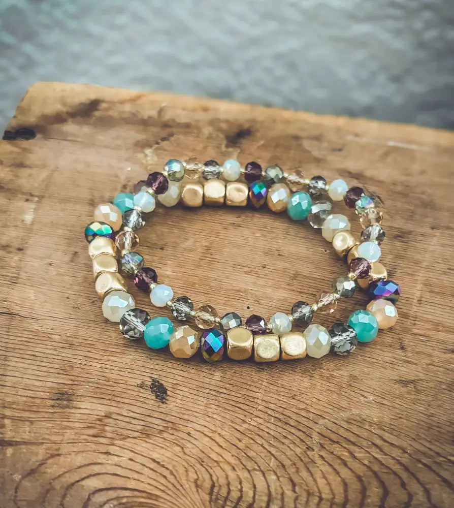 Bohemian earth tone iridescent beaded stretch bracelet with gold teal purple faceted beads and metallic accents