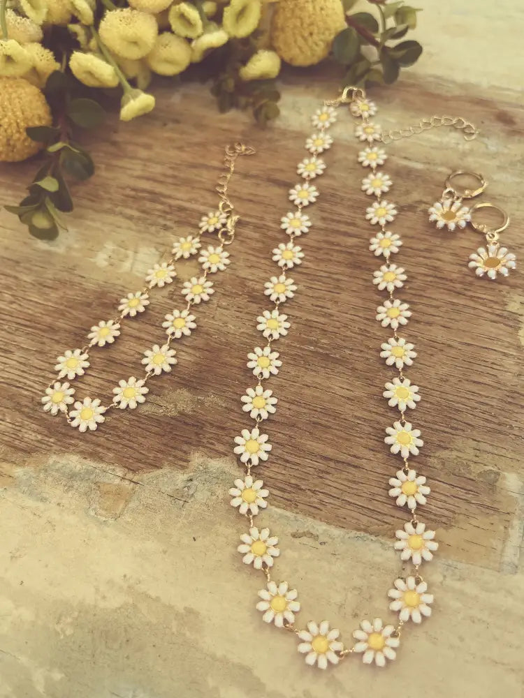 Gold daisy enamel necklace with delicate gold tone chain and white enamel daisy charms with yellow centers