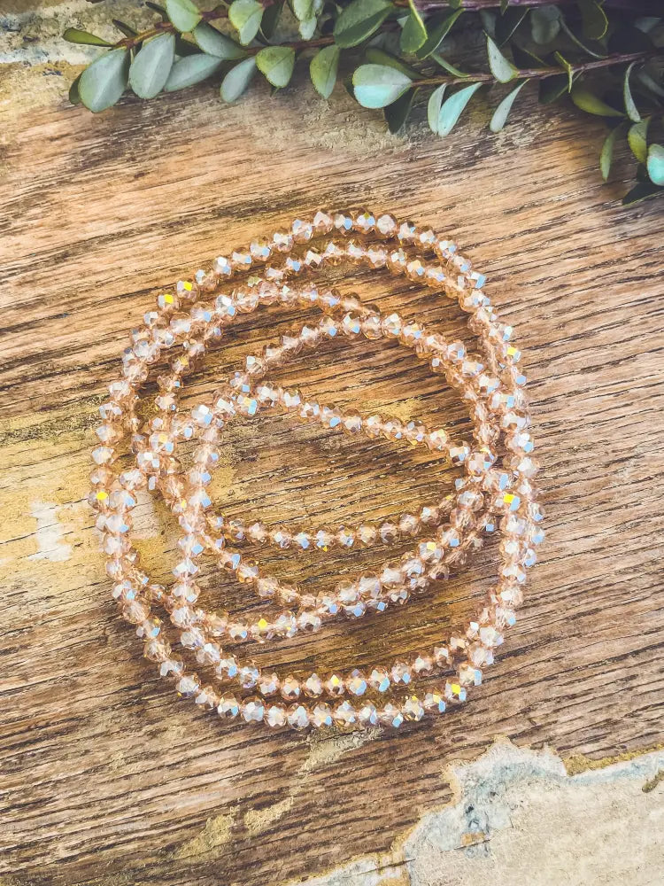 A rose gold multi strand faceted crystal bead bracelet with delicate beads arranged in a coiled pattern