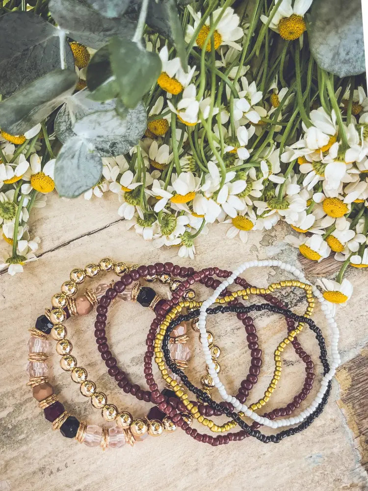 Gold and burgundy earthy beaded stacking bracelet set with gold-toned metallic beads and translucent pink crystals