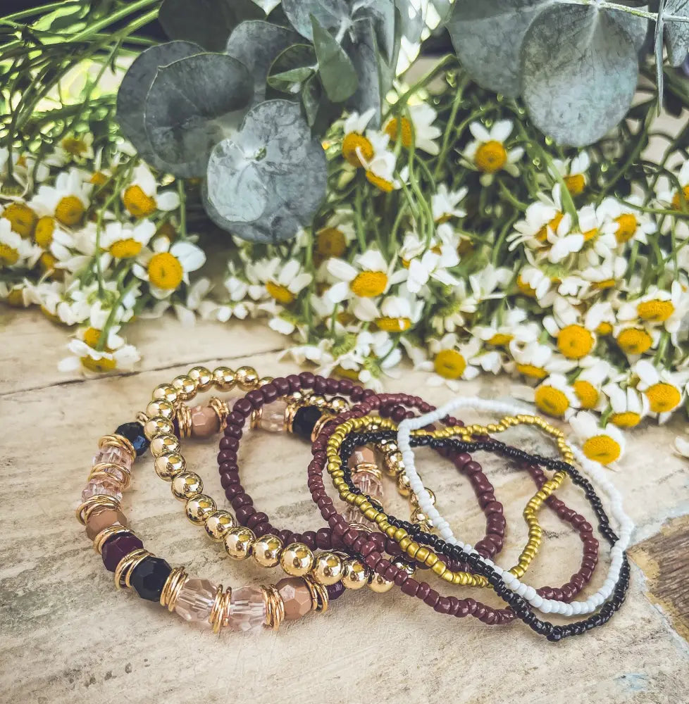 A gold and burgundy earthy beaded stacking bracelet set with stretch bands gold-toned beads and clear crystal accents