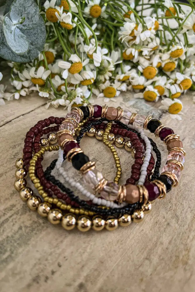 A set of five gold and burgundy earthy beaded stacking bracelets with stretchy mixed gemstone beads and gold accents