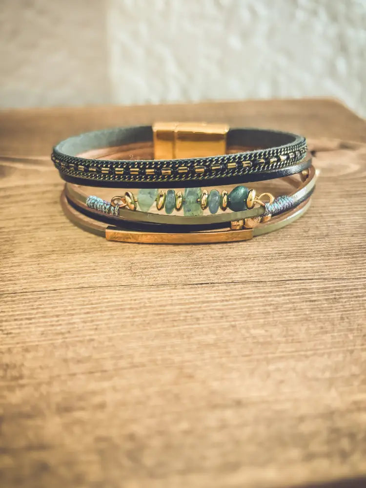 Layered green gemstone and leather magnetic bracelet set with dark leather bands gold-toned clasps and green gemstone strand