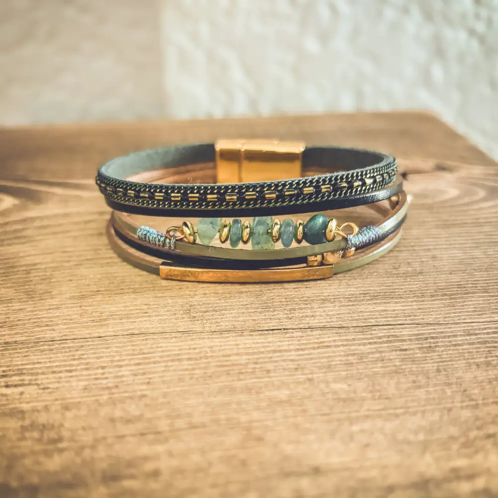 Layered green gemstone and leather magnetic bracelet with dark leather bands gold-tone accents and central green gemstones