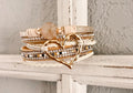 Layered rose quartz and leather heart charm bracelet with gold tones, rhinestones, and textured druzy stone accents