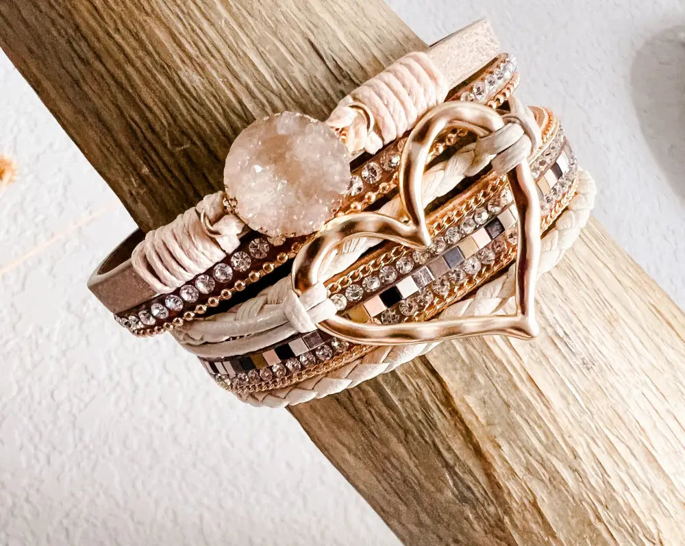 Layered rose quartz and leather heart charm bracelet set featuring rose gold and beige tones with crystal accents and woven detailing
