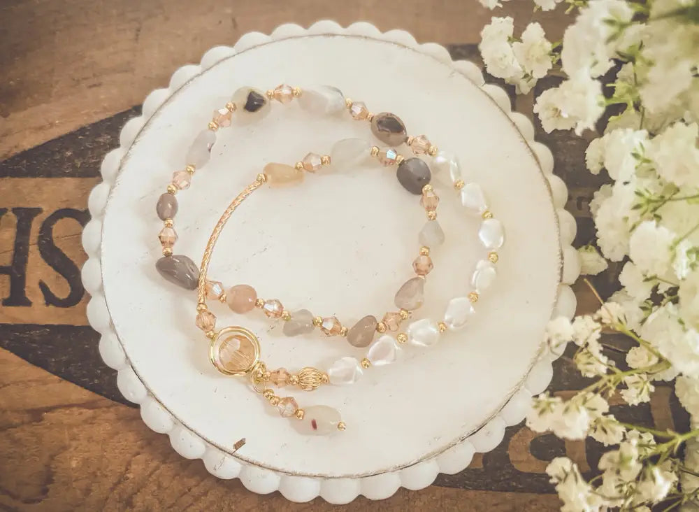 A pearl and crystal beaded gold charm bracelet with translucent and opaque pastel stones and a central circular charm