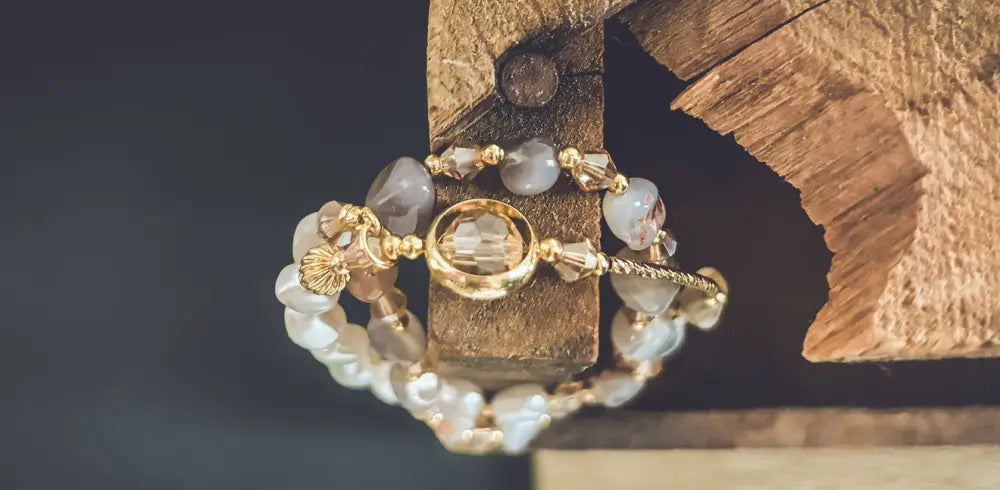 Pearl and crystal beaded gold charm bracelet with translucent gray and white stones and central faceted crystal charm