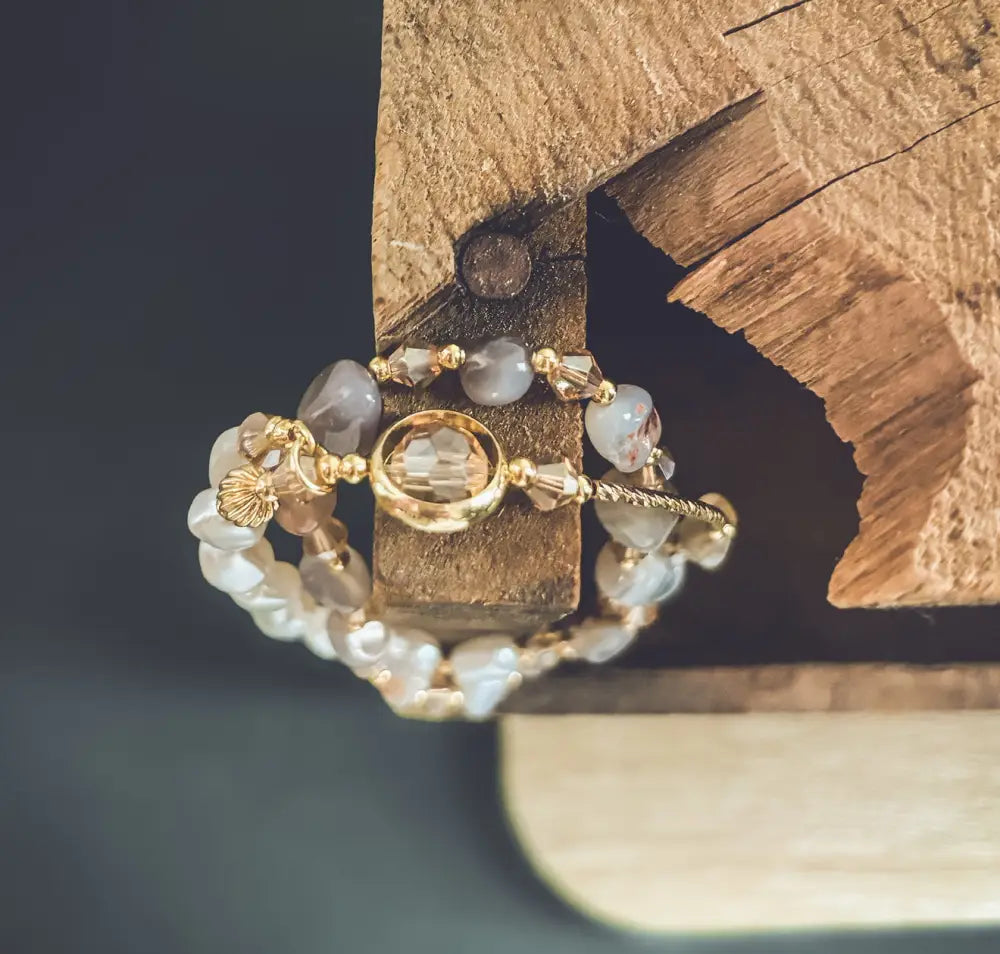 A gold-toned pearl and crystal beaded charm bracelet with a central oval crystal and scattered pearl-like beads