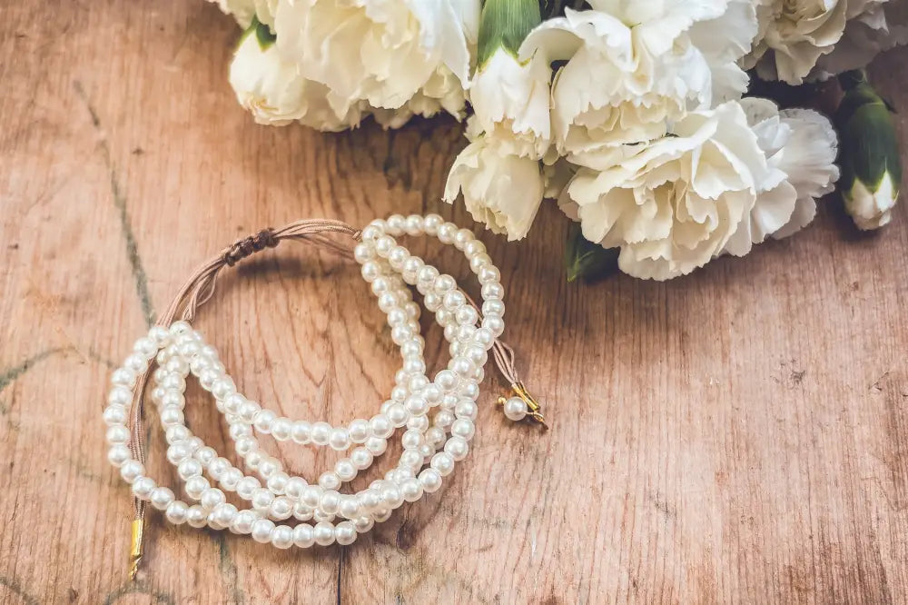 A delicate multi-strand pearl bracelet with a braided cord gold clasp in soft white with a subtle sheen