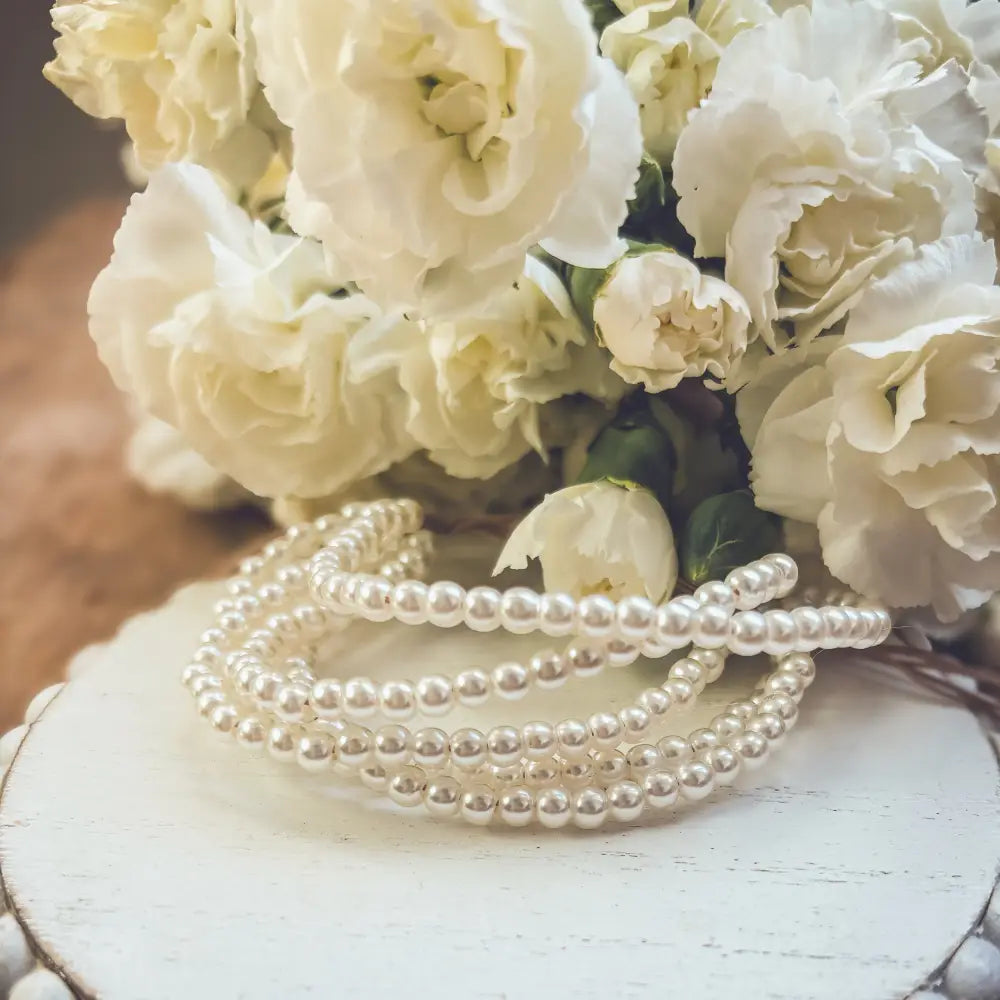 Multi-strand pearl bracelet with braided cord and gold clasp featuring lustrous white beads in a coiled design