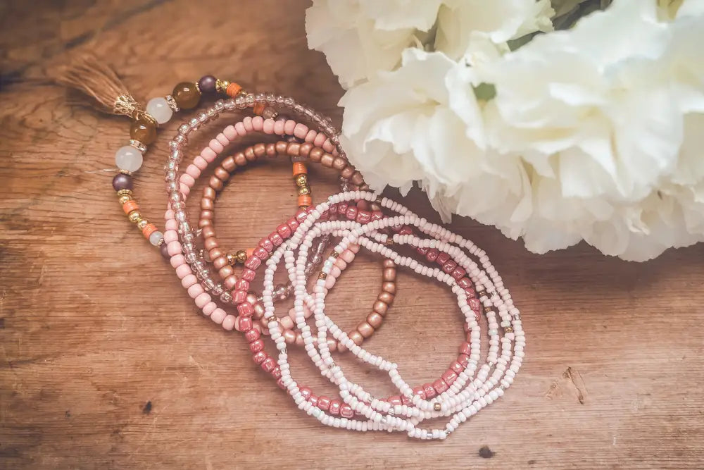 Pink and earth tone beaded tassel stacking bracelet set with delicate pink peach cream beads and subtle metallic accents