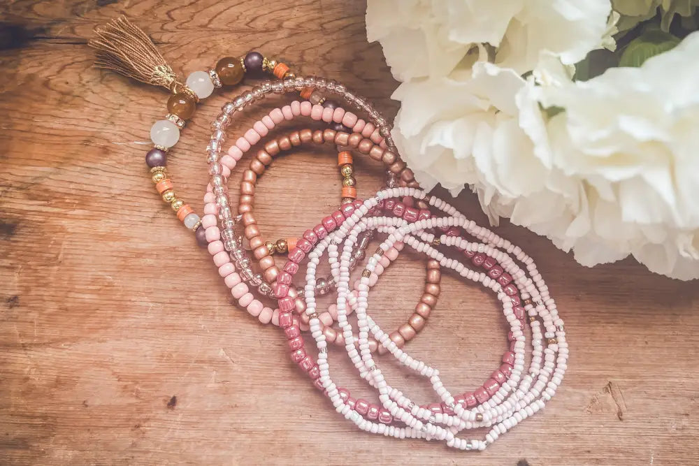Pink and earth tone beaded tassel stacking bracelet set with delicate beads in soft pink peach white and metallic accents
