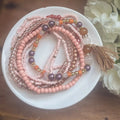 A set of delicate pink mauve and gold-toned beaded stacking bracelets with a matching tassel accent