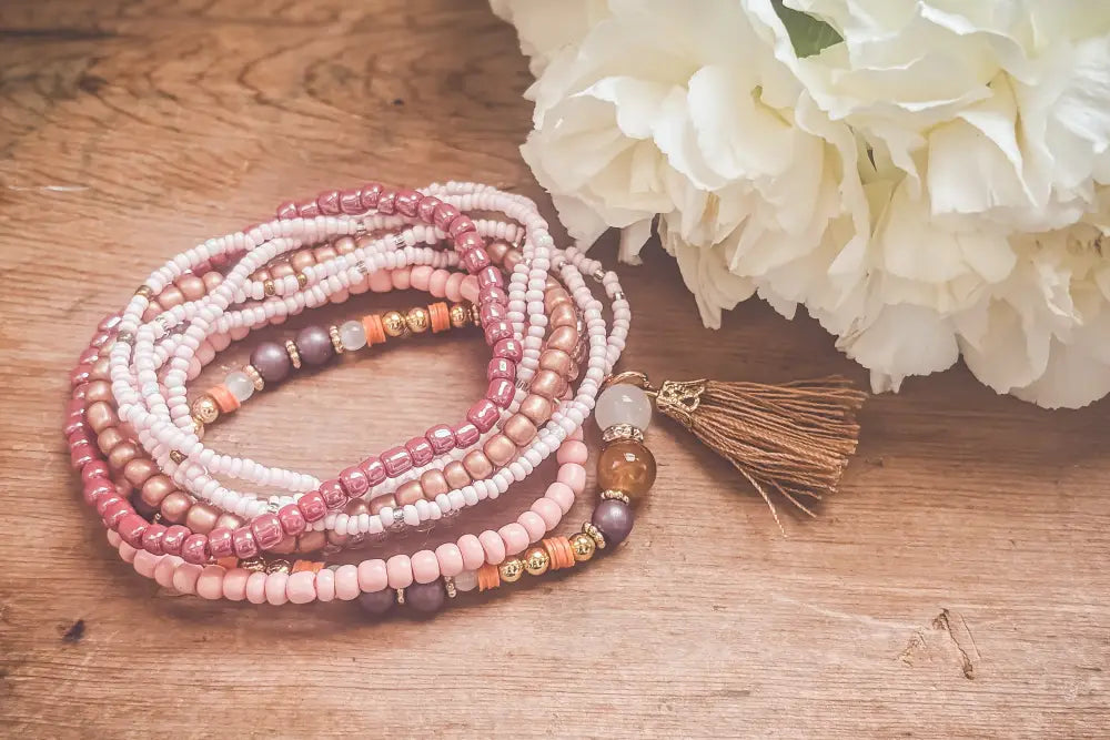 A delicate pink and earth tone beaded tassel stacking bracelet set with soft hues and metallic accents