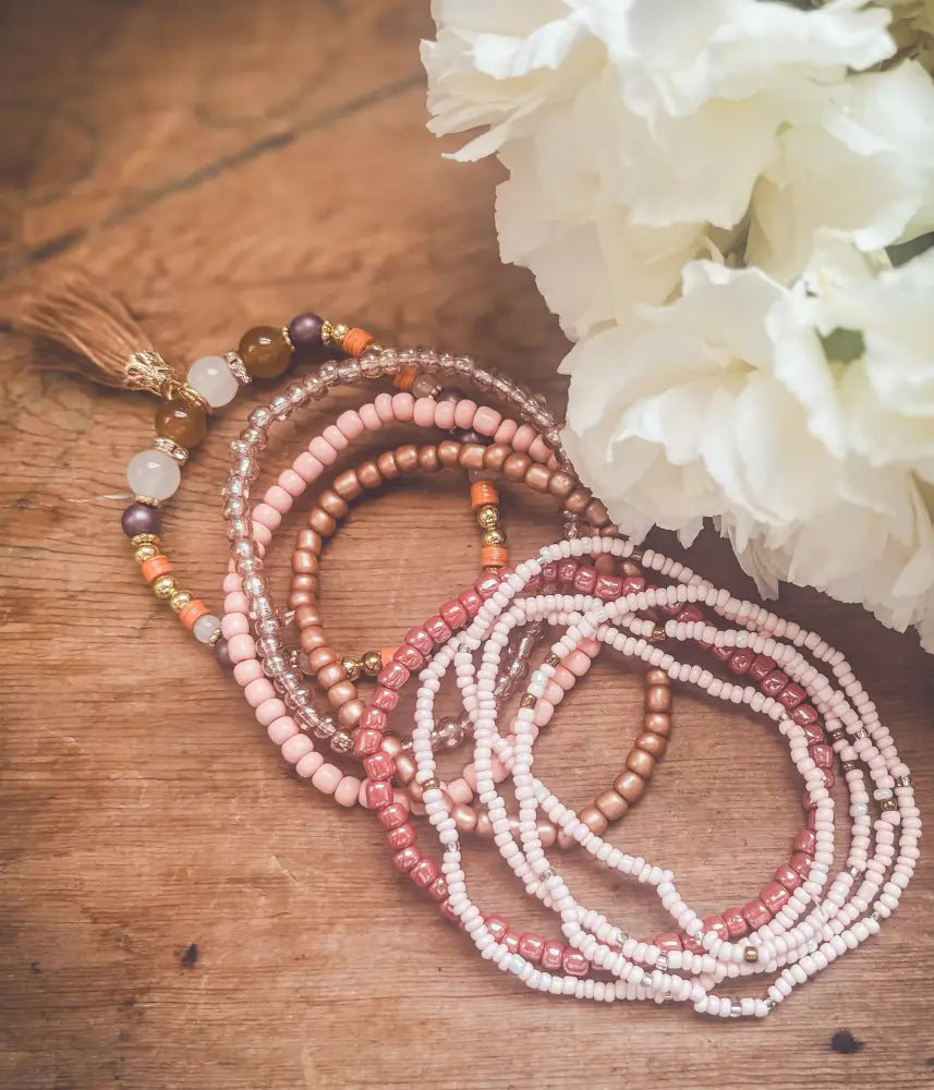 Pink and earth tone beaded tassel stacking bracelet set featuring delicate beadwork in soft pink peach and metallic tones