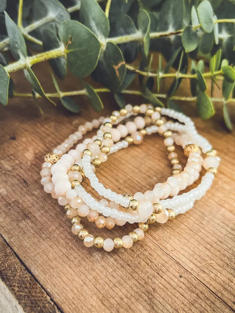 Elegant pink and gold beaded stacking bracelet set featuring multi-strand peach and white translucent beads with gold spheres