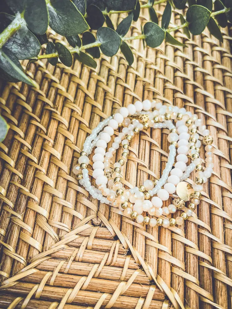 Elegant pink and gold beaded stacking bracelet set featuring delicate white and pale blue stone beads with gold accents