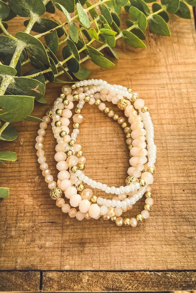 A delicate stack of elegant pink and gold beaded stretch bracelets with faceted glass and metallic accents