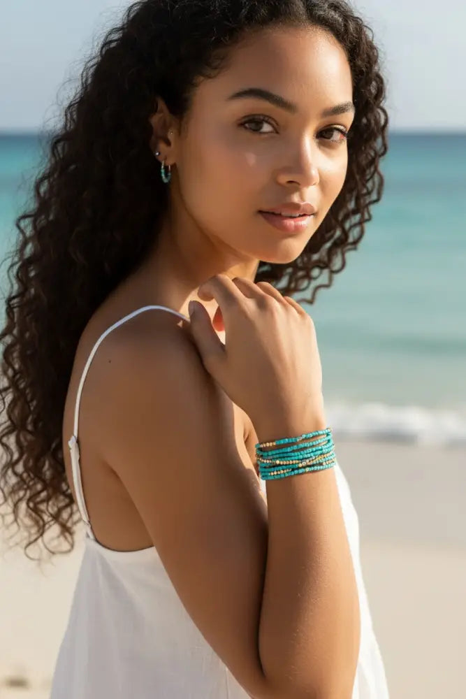 A stack of boho turquoise and gold beaded stacking wrap bracelets worn on a wrist