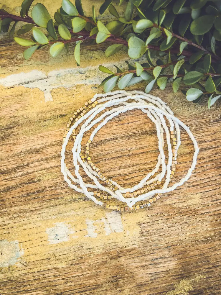 A delicate white and gold beaded multi strand stacking bracelet featuring square beads arranged in a coiled pattern