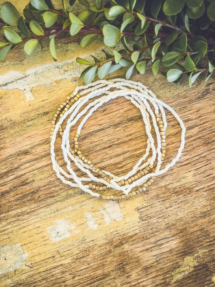 White and gold beaded multi strand stacking bracelet set featuring delicate alternating beads with a woven texture
