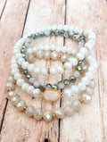 Stacked white and blue beaded bracelets with faceted stones gold spacers and hexagonal druzy pendant