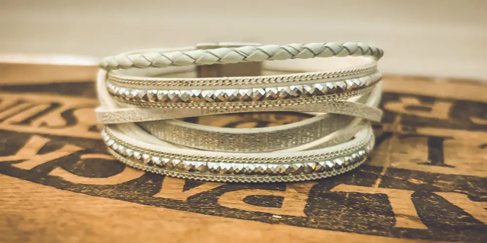 White layered leather wrap bracelet featuring braided and beaded detailing with silver-toned accents