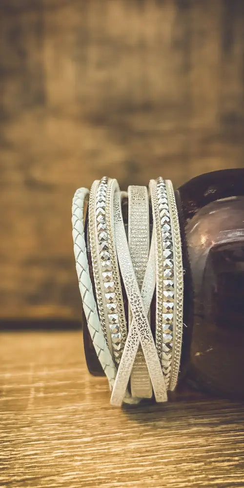 White layered leather wrap bracelet with silver accents featuring braided and rhinestone-embellished silver-toned bands