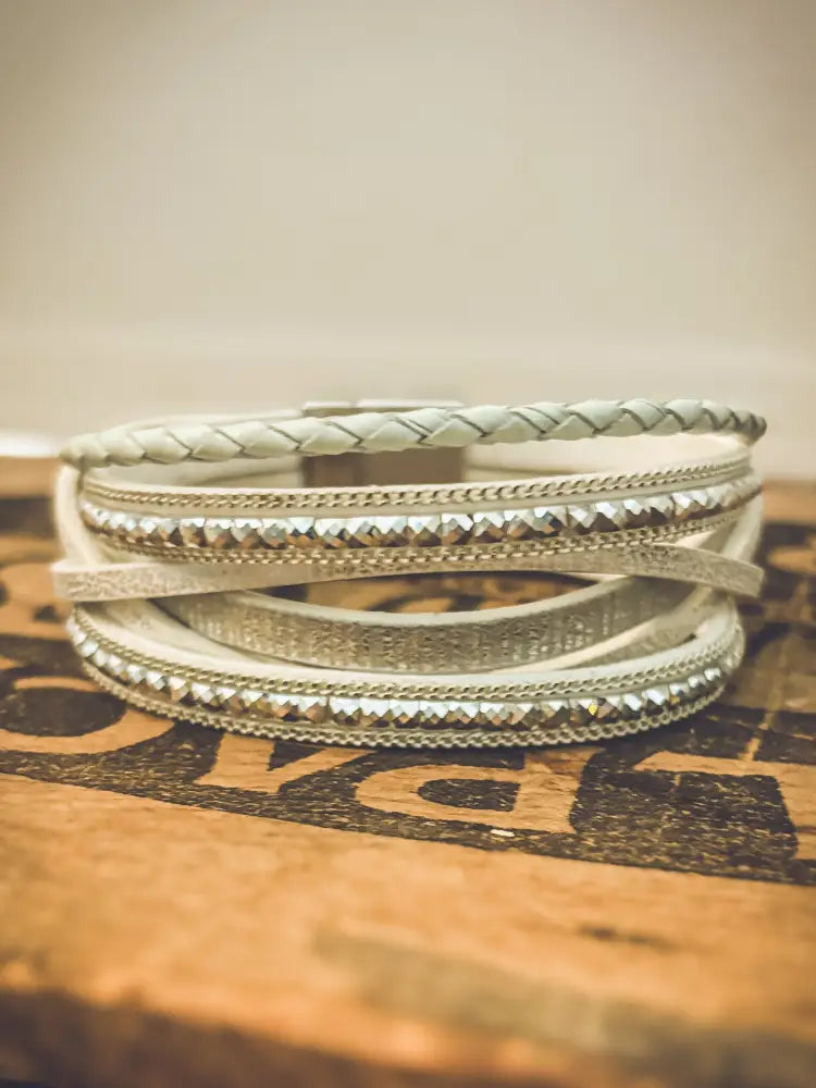 White layered leather wrap bracelet with silver-toned metallic accents and braided texture displayed front view