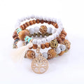 A set of five layered white tree of life beaded stacking bracelets with wooden white marble and turquoise beads with gold accents
