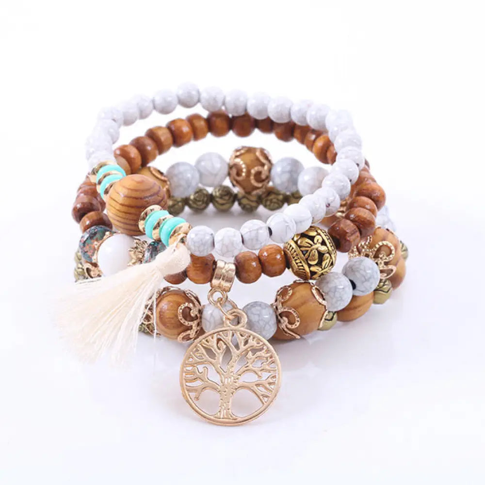 A set of five layered white tree of life beaded stacking bracelets with wooden white marble and turquoise beads with gold accents